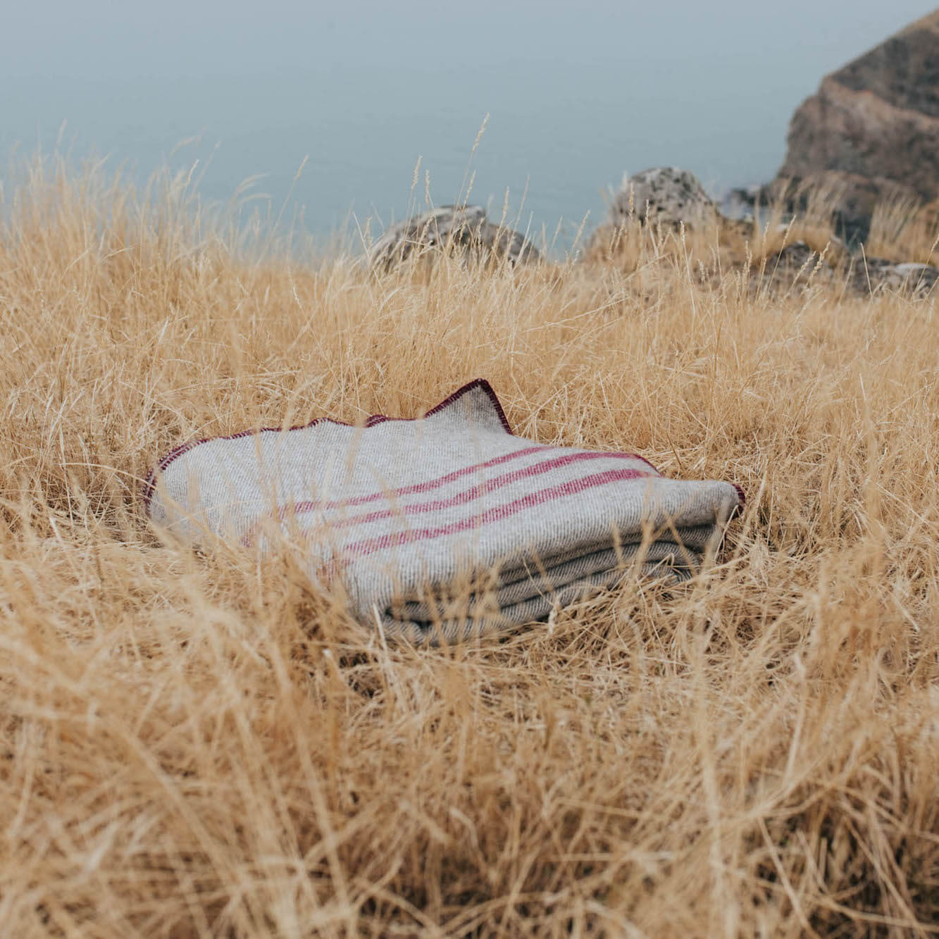 Pure wool cabin blanket on dry grass, showcasing traditional craftsmanship and durability in natural surroundings.
