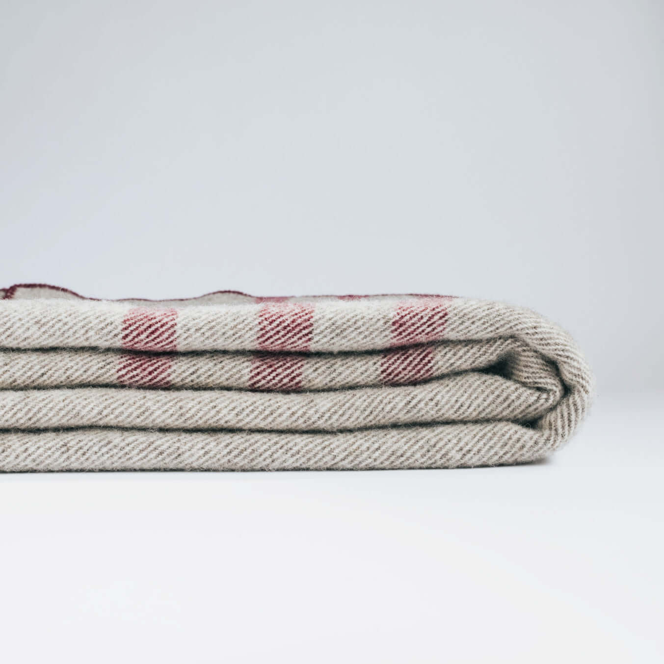 Folded pure wool cabin blanket featuring a checkered pattern, showcasing its softness and traditional craftsmanship.