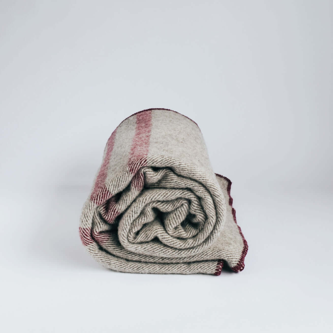 Rolled pure wool cabin blanket with red stripes, soft and warm, perfect for queen-sized beds.